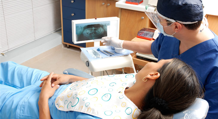 Dentist sits with patient while he discusses her oral X-ray results