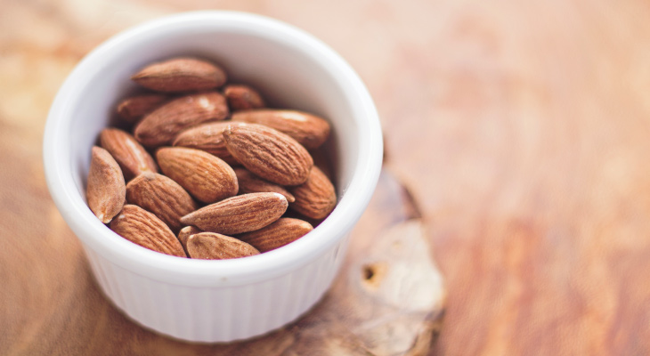 Aerial view of brown almonds in a white custard cup that promote healthy teeth