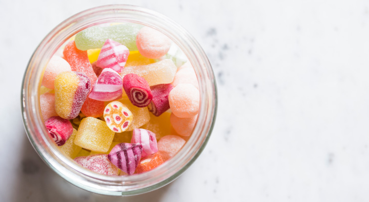 Aerial view of colorful candies in a clear jar on a marble counter