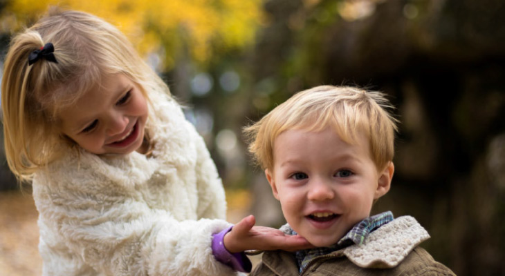 young girl showing off her baby brother's teeth and smile