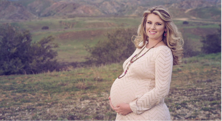pregnant woman standing outside in a field