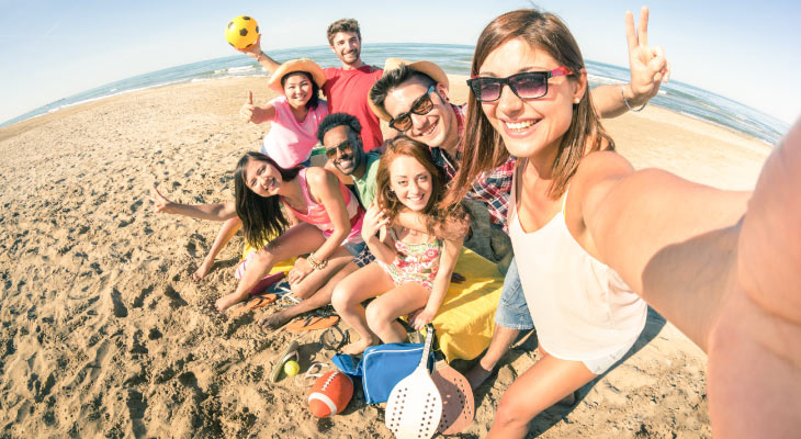 Group of friends smile while hanging out on the beach in the summer