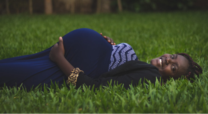 pregnant woman laying in the grass holding her belly