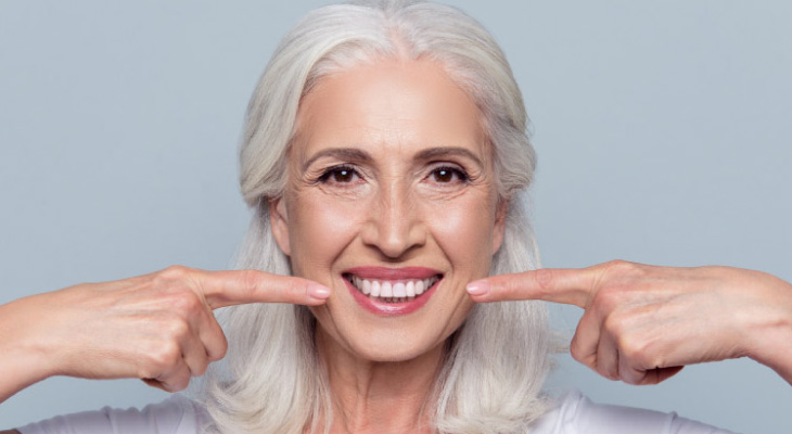 woman pointing to her white teeth with both forefingers after cosmetic dentistry