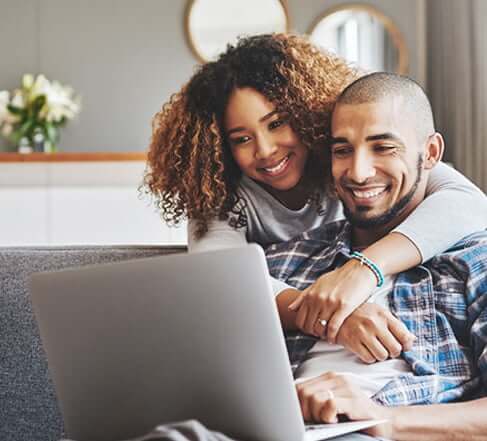 couple smiling in front of a computer
