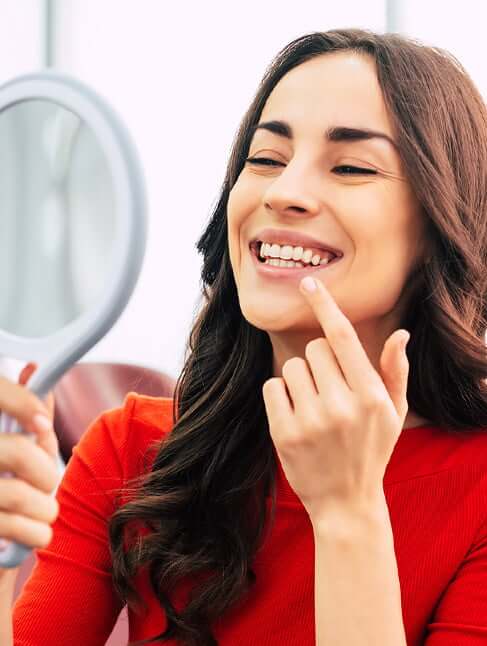 woman with a mirror looking at smile